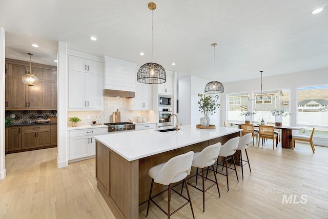 kitchen with a spacious island, white cabinetry, hanging light fixtures, stainless steel oven, and built in microwave