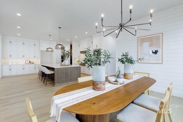 dining space featuring wooden walls, a chandelier, and light wood-type flooring