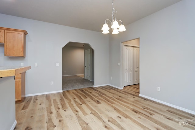 10224 W Altair, Star, ID 83669 - unfurnished dining area with arched walkways, light wood-type flooring, and a chandelier