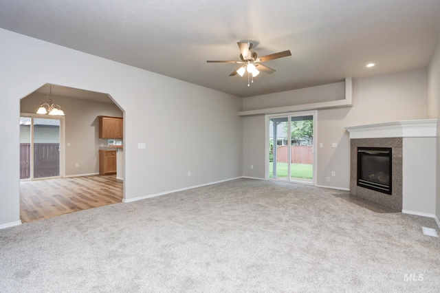 10224 W Altair, Star, ID 83669 - unfurnished living room featuring carpet, a ceiling fan, a tiled fireplace, a chandelier, and arched walkways