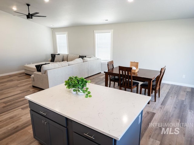 13743 S Sonata Way, Nampa, ID 83651 - kitchen with a kitchen island, a ceiling fan, open floor plan, baseboards, and wood finished floors