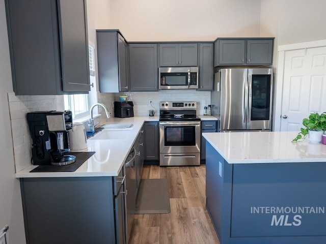 13743 S Sonata Way, Nampa, ID 83651 - kitchen with stainless steel appliances, a sink, light wood finished floors, decorative backsplash, and light stone counters