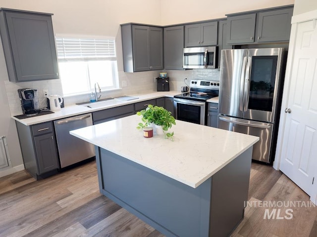 13743 S Sonata Way, Nampa, ID 83651 - kitchen featuring stainless steel appliances, a sink, backsplash, light wood-style floors, and a center island