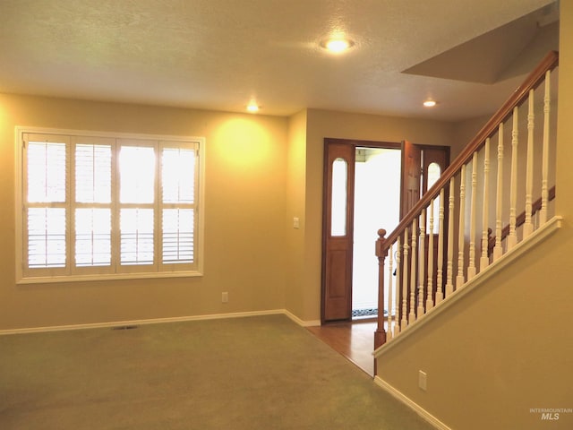 carpeted entryway featuring a textured ceiling