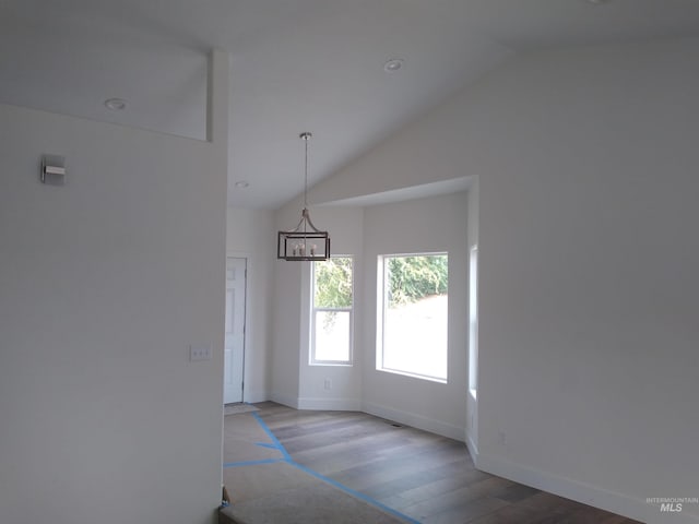 empty room featuring a chandelier, hardwood / wood-style floors, and lofted ceiling