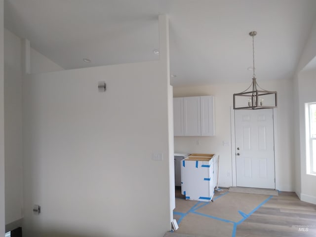 laundry area with light hardwood / wood-style floors and a notable chandelier