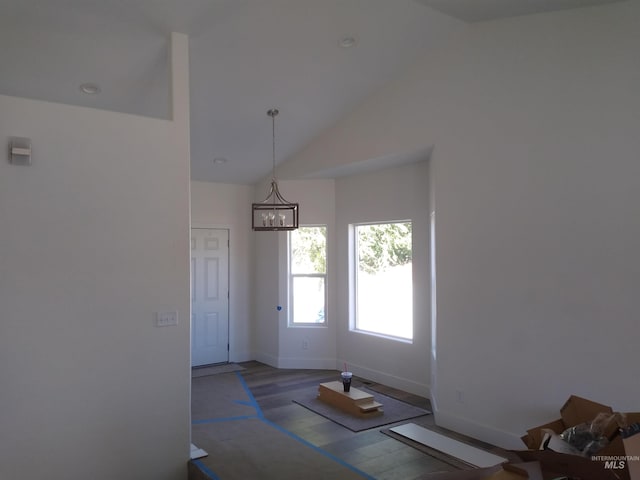 unfurnished dining area featuring a chandelier, hardwood / wood-style floors, and high vaulted ceiling