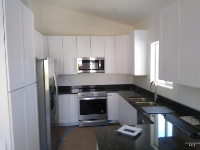 kitchen featuring white cabinetry, sink, stainless steel appliances, and vaulted ceiling