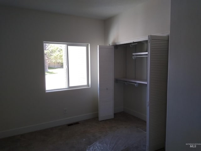 unfurnished bedroom featuring dark carpet and a closet