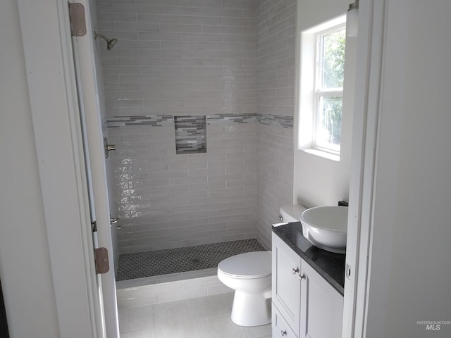 bathroom featuring tile patterned floors, vanity, a tile shower, and toilet