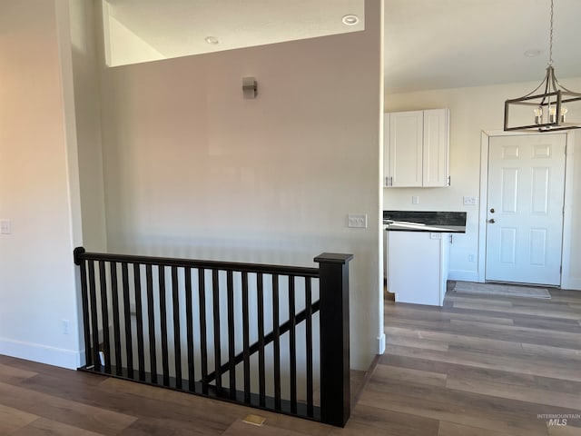 corridor with hardwood / wood-style flooring and an inviting chandelier