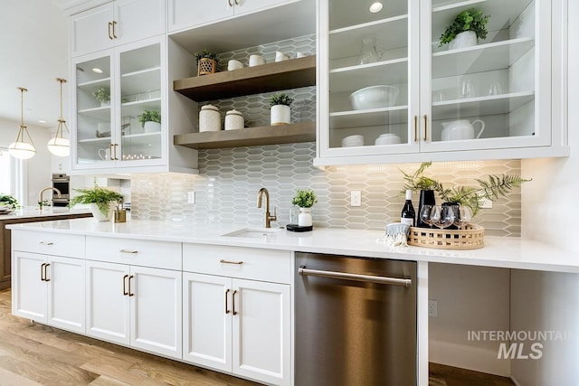 bar with appliances with stainless steel finishes, hanging light fixtures, white cabinetry, light wood-type flooring, and sink