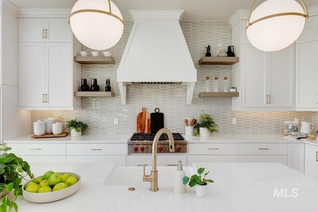 kitchen featuring white cabinets, custom exhaust hood, decorative light fixtures, and decorative backsplash