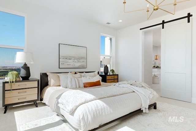 bedroom with a barn door, carpet, connected bathroom, and a chandelier