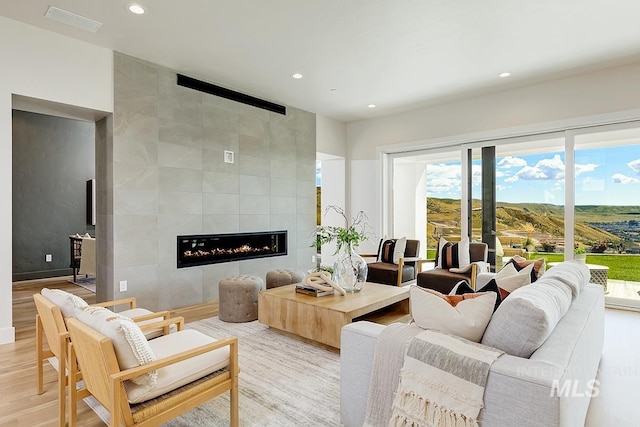 living room with light hardwood / wood-style flooring, a healthy amount of sunlight, and a tile fireplace