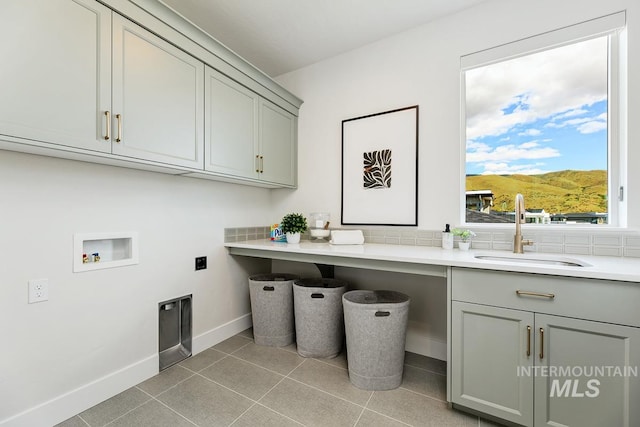 clothes washing area featuring washer hookup, a mountain view, light tile patterned flooring, sink, and cabinets