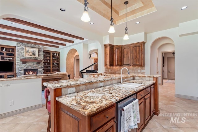 215 W Riverbridge Ln, Eagle, ID 83616 - kitchen with arched walkways, light stone counters, a fireplace, beam ceiling, and tasteful backsplash