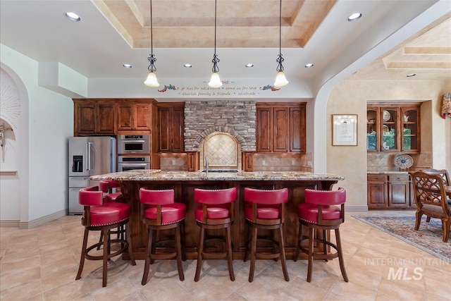 215 W Riverbridge Ln, Eagle, ID 83616 - kitchen featuring high quality fridge, arched walkways, a tray ceiling, decorative backsplash, and recessed lighting