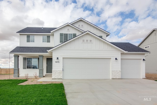 view of front of property with board and batten siding, a front lawn, an attached garage, a shingled roof, and concrete driveway