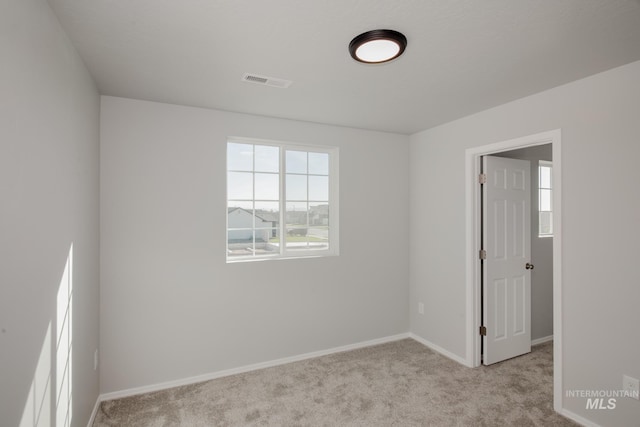 carpeted spare room featuring visible vents and baseboards