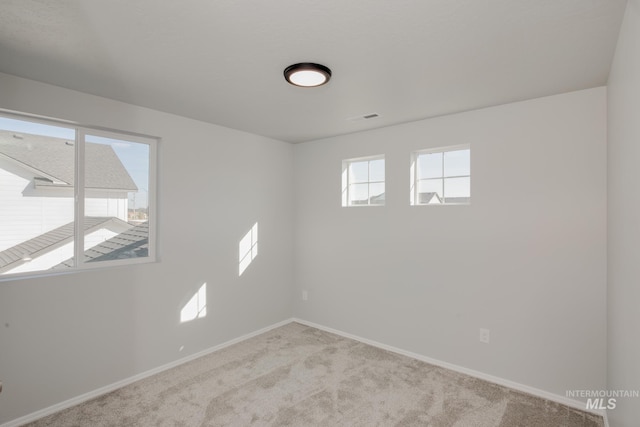 unfurnished room featuring visible vents, baseboards, and carpet flooring