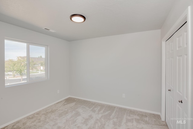 unfurnished bedroom with a closet, light colored carpet, baseboards, and visible vents