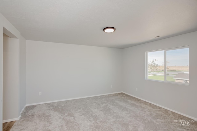 spare room with baseboards and carpet