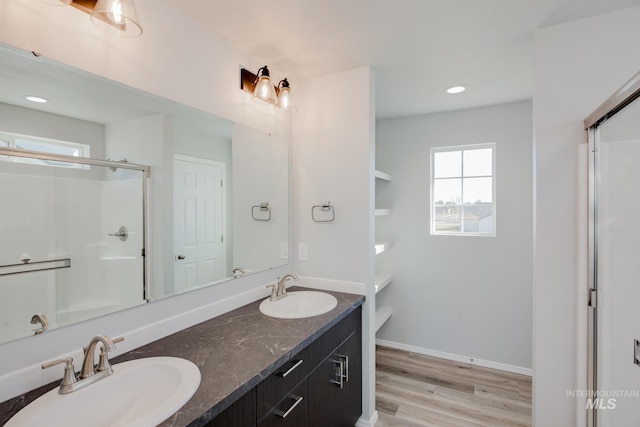 full bathroom with a shower stall, wood finished floors, double vanity, and a sink