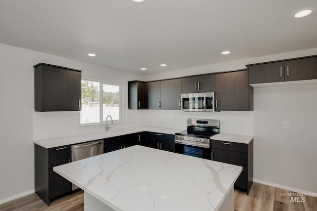 kitchen featuring a sink, a center island, light wood-style floors, and stainless steel appliances