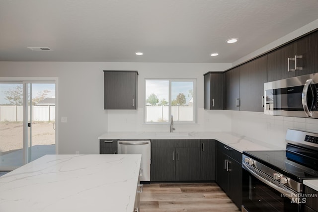 kitchen featuring stainless steel appliances, plenty of natural light, a sink, and decorative backsplash