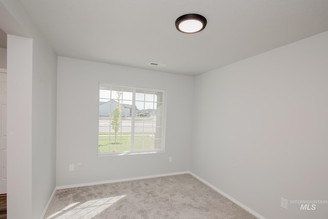 spare room featuring carpet floors, baseboards, and visible vents