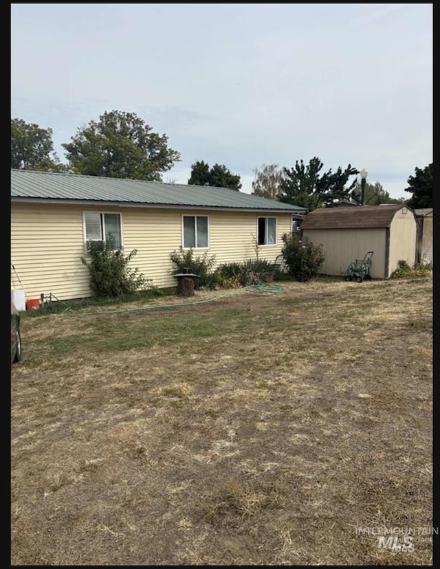 view of front of property with a front yard, metal roof, an outdoor structure, and a storage shed