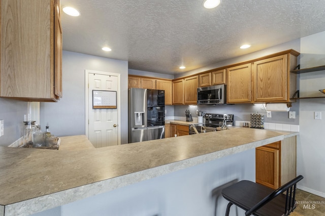 kitchen featuring stainless steel appliances, recessed lighting, light countertops, a textured ceiling, and a peninsula