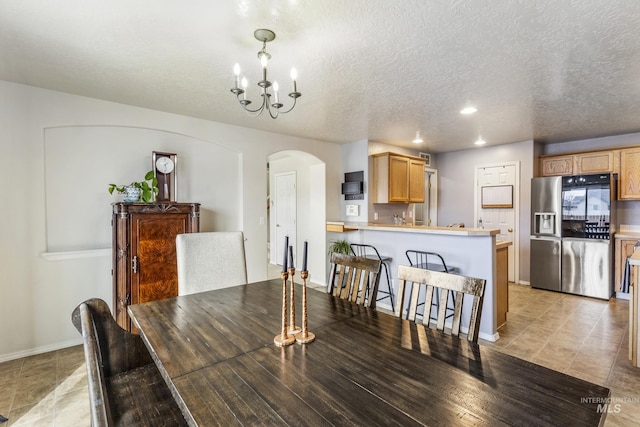 dining area featuring baseboards, arched walkways, a chandelier, and a textured ceiling