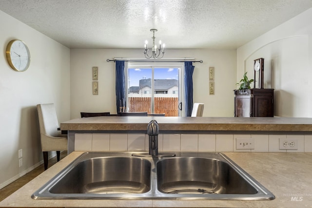 interior details featuring a textured ceiling, a sink, and a notable chandelier