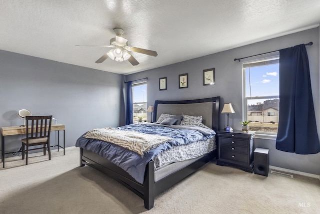 carpeted bedroom with a ceiling fan, visible vents, a textured ceiling, and baseboards