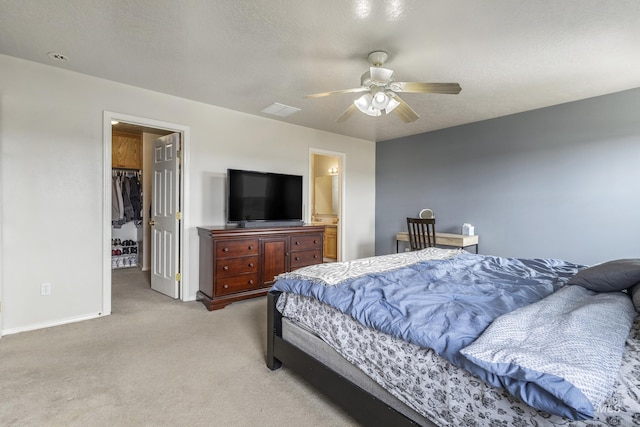 bedroom featuring visible vents, a walk in closet, a textured ceiling, and light colored carpet