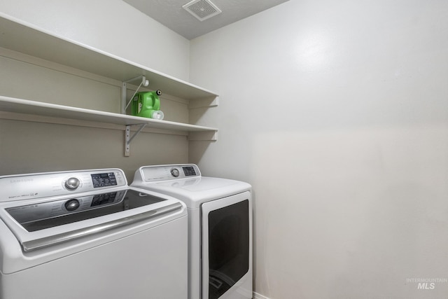 washroom with laundry area, separate washer and dryer, and visible vents