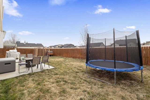 view of yard featuring a trampoline, a patio area, and a fenced backyard