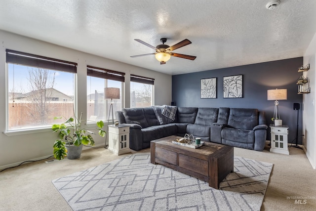 living area featuring carpet floors, a textured ceiling, and a ceiling fan