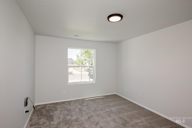 spare room with visible vents, baseboards, and light colored carpet