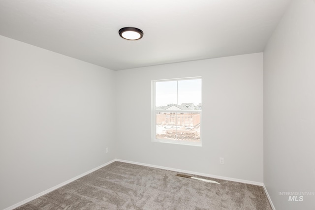 unfurnished room featuring light carpet and baseboards