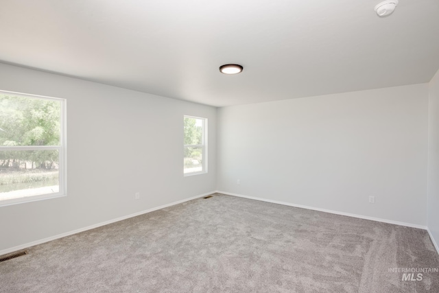 spare room featuring visible vents, light carpet, and baseboards