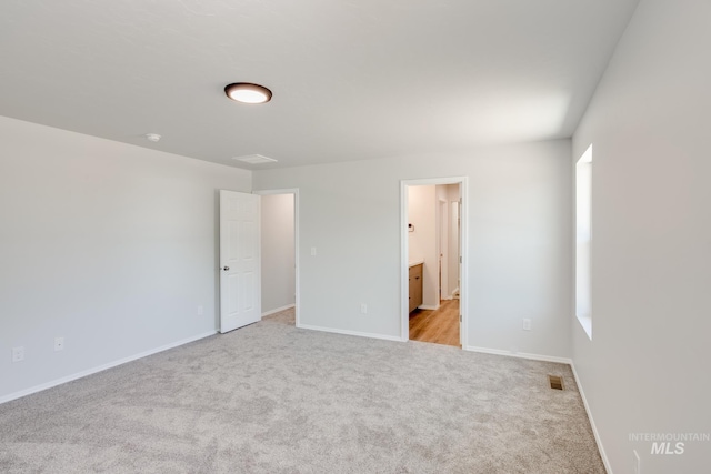 unfurnished bedroom featuring light colored carpet, visible vents, baseboards, and ensuite bathroom