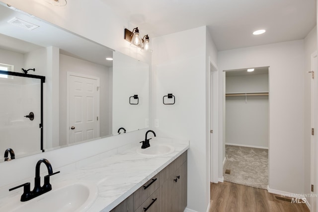 bathroom with double vanity, a spacious closet, visible vents, and a sink