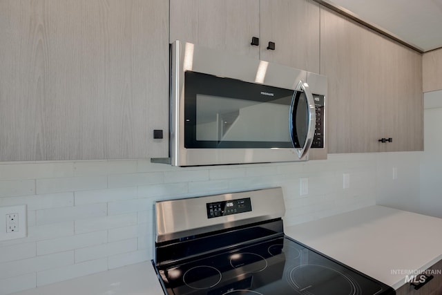 kitchen featuring stainless steel appliances, light countertops, light brown cabinetry, tasteful backsplash, and modern cabinets