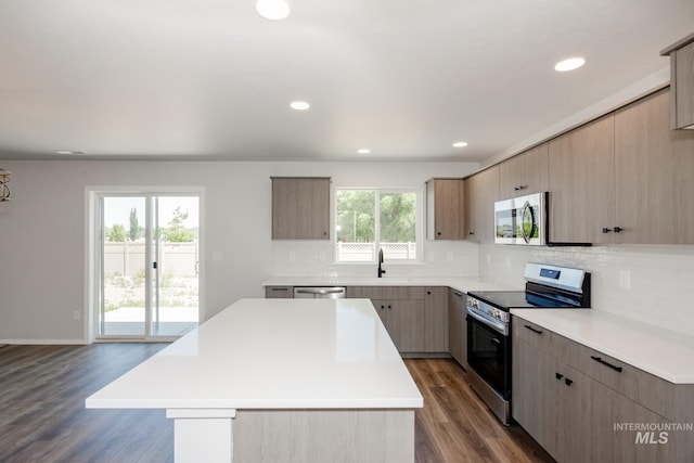 kitchen with a kitchen island, appliances with stainless steel finishes, light countertops, and dark wood-style flooring