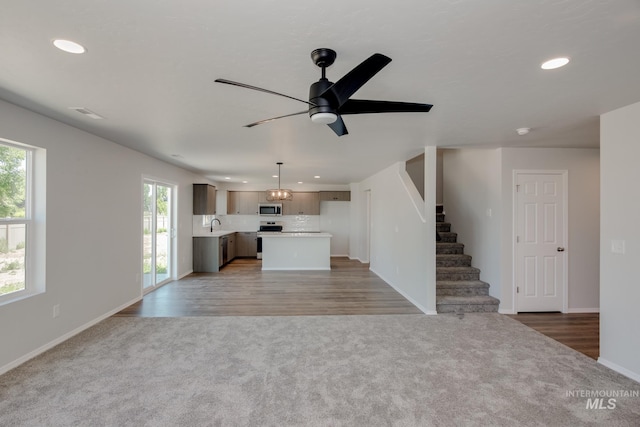 unfurnished living room with ceiling fan, recessed lighting, baseboards, stairs, and carpet