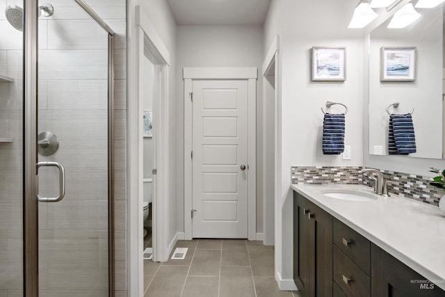 bathroom featuring decorative backsplash, tile patterned floors, walk in shower, vanity, and toilet