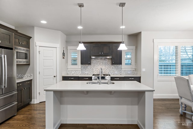 kitchen with pendant lighting, stainless steel appliances, dark brown cabinets, and sink